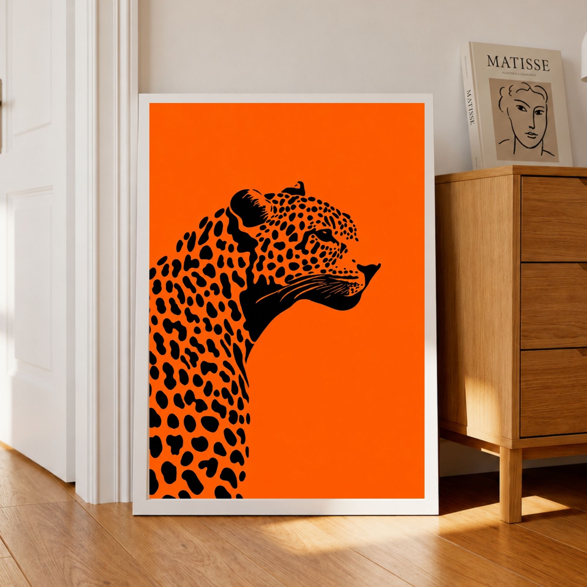 Orange leopard poster in a black frame leaning on a corner living room wall